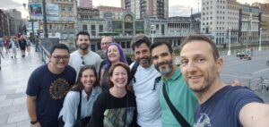 A group of CHAOSS community members taking a selfie on the bridge leading to the Bilbao old town area