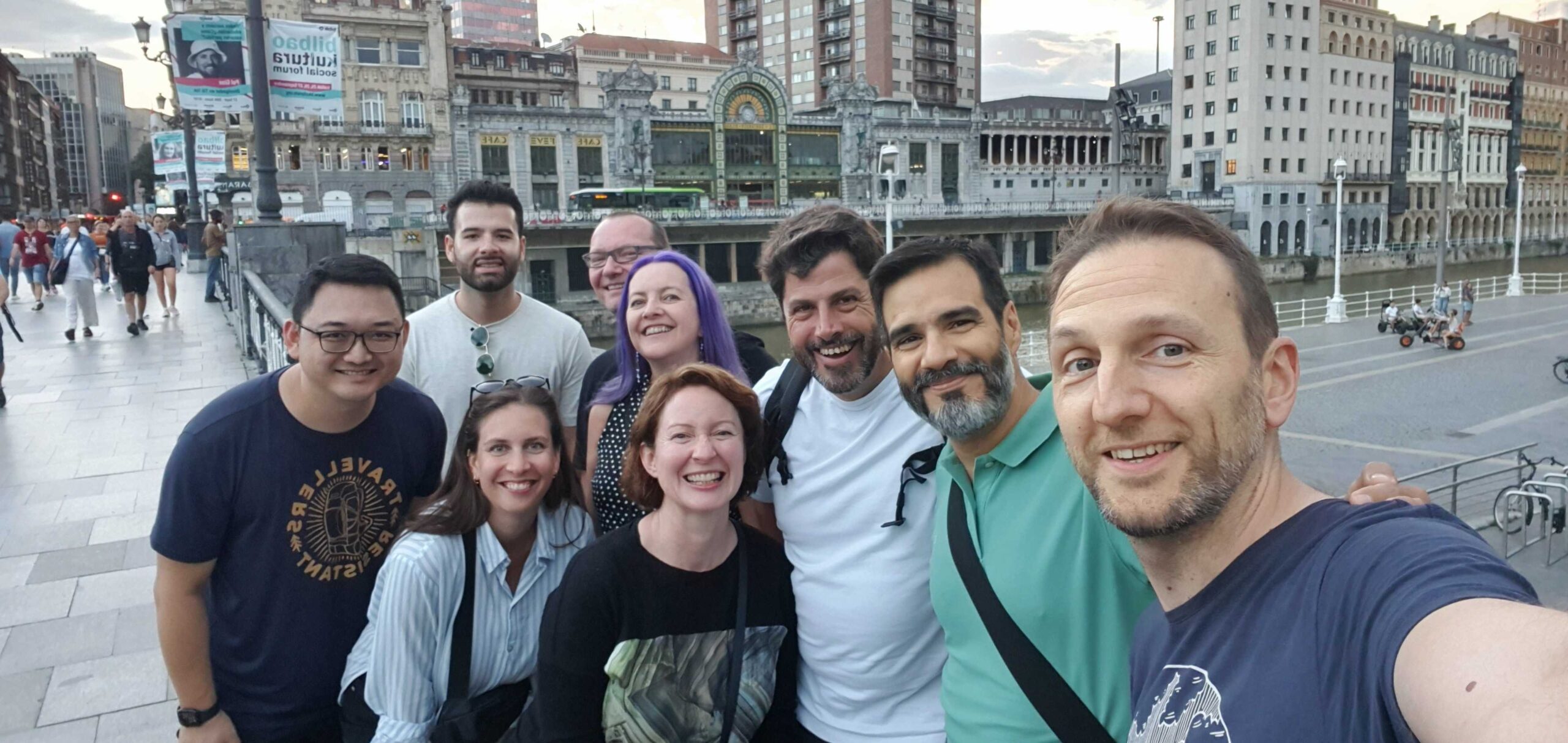 A group of CHAOSS community members taking a selfie on the bridge leading to the Bilbao old town area