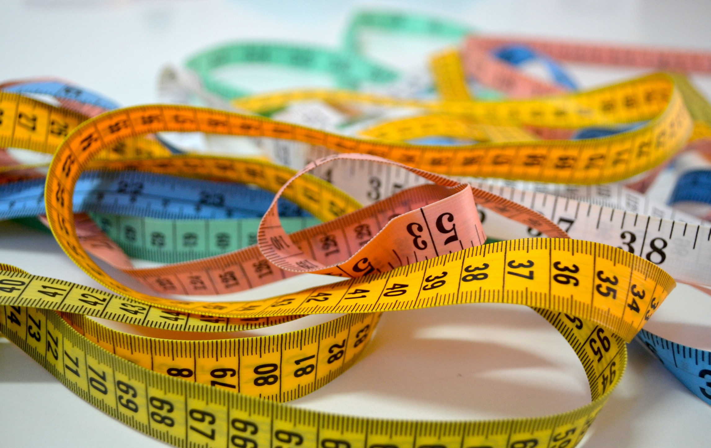 Pile of intertwined measuring tapes of various colors