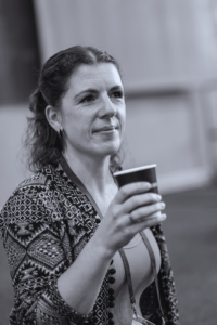 black and white photo of a white woman with brown hair holding a cup of coffee