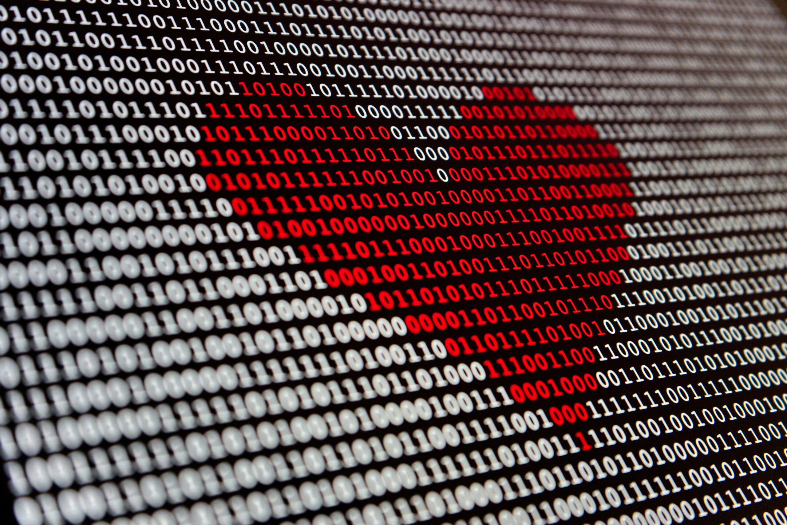 A bunch of white ones and zeros on a black background with a heart shape of ones and zeros in the middle