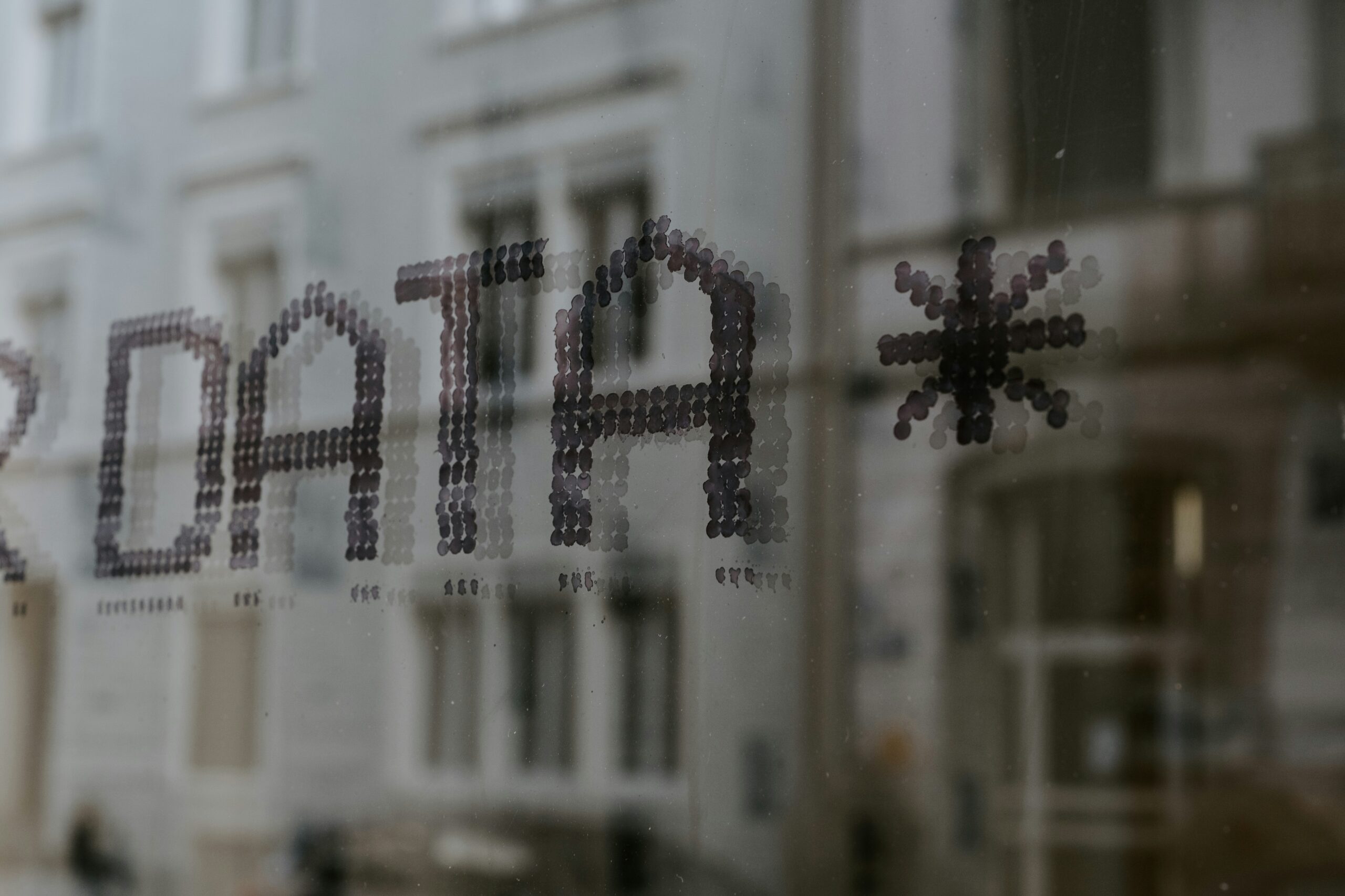 Close up of a window with reflections of buildings. Window has a sign that reads "DATA *"